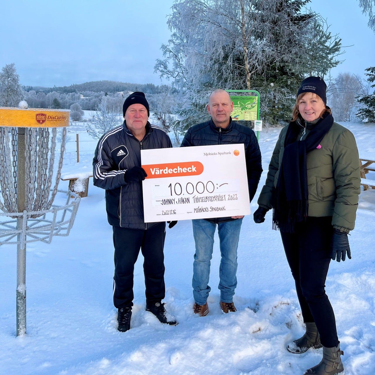 Lena räcker över prischecken till vinnarna av Trivselbygdspriset 2022 Johnny Eriksson och Håkan Eriksson.