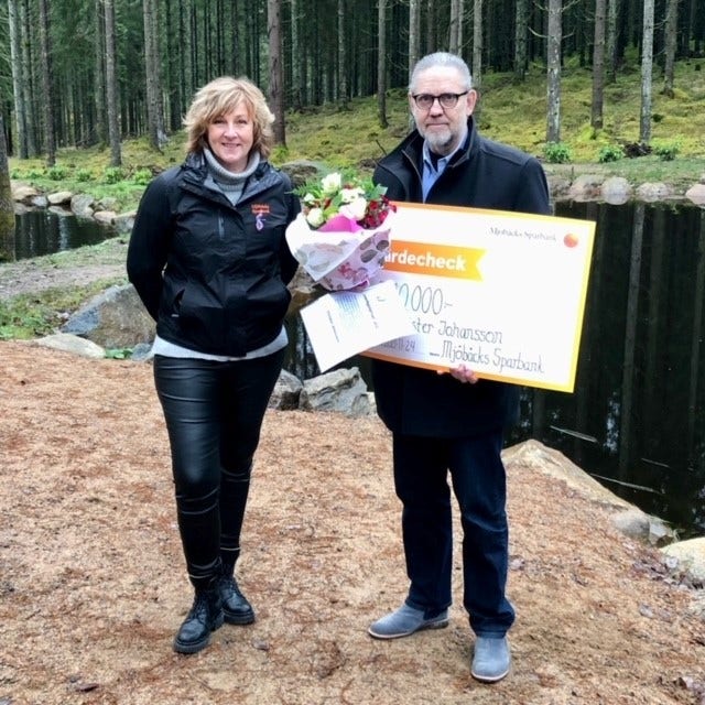 Lena Karlsson räcker över Trivselbygdspriset 2021 till vinnaren Christer Johansson