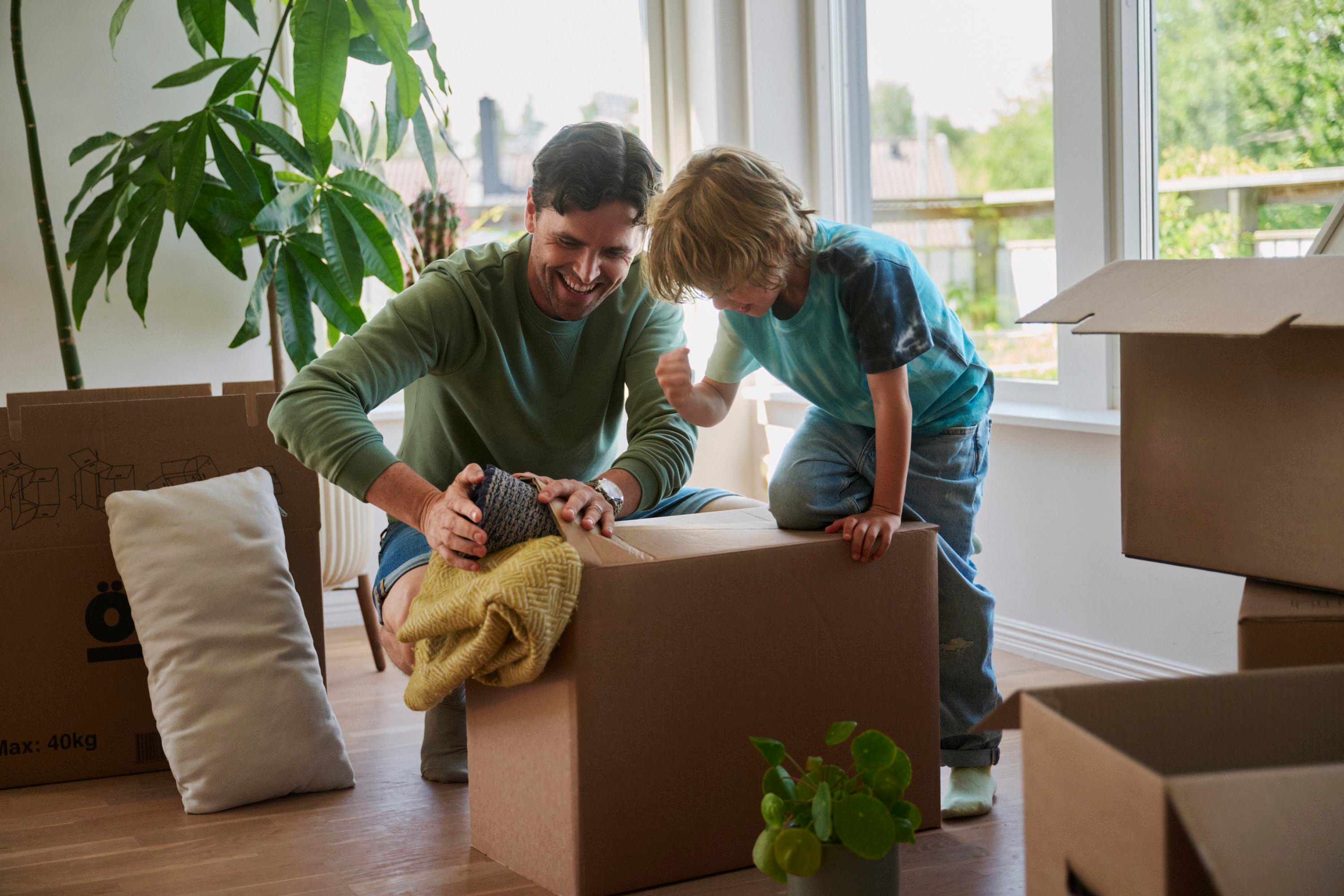 En man och ett litet barn packar flyttkartonger