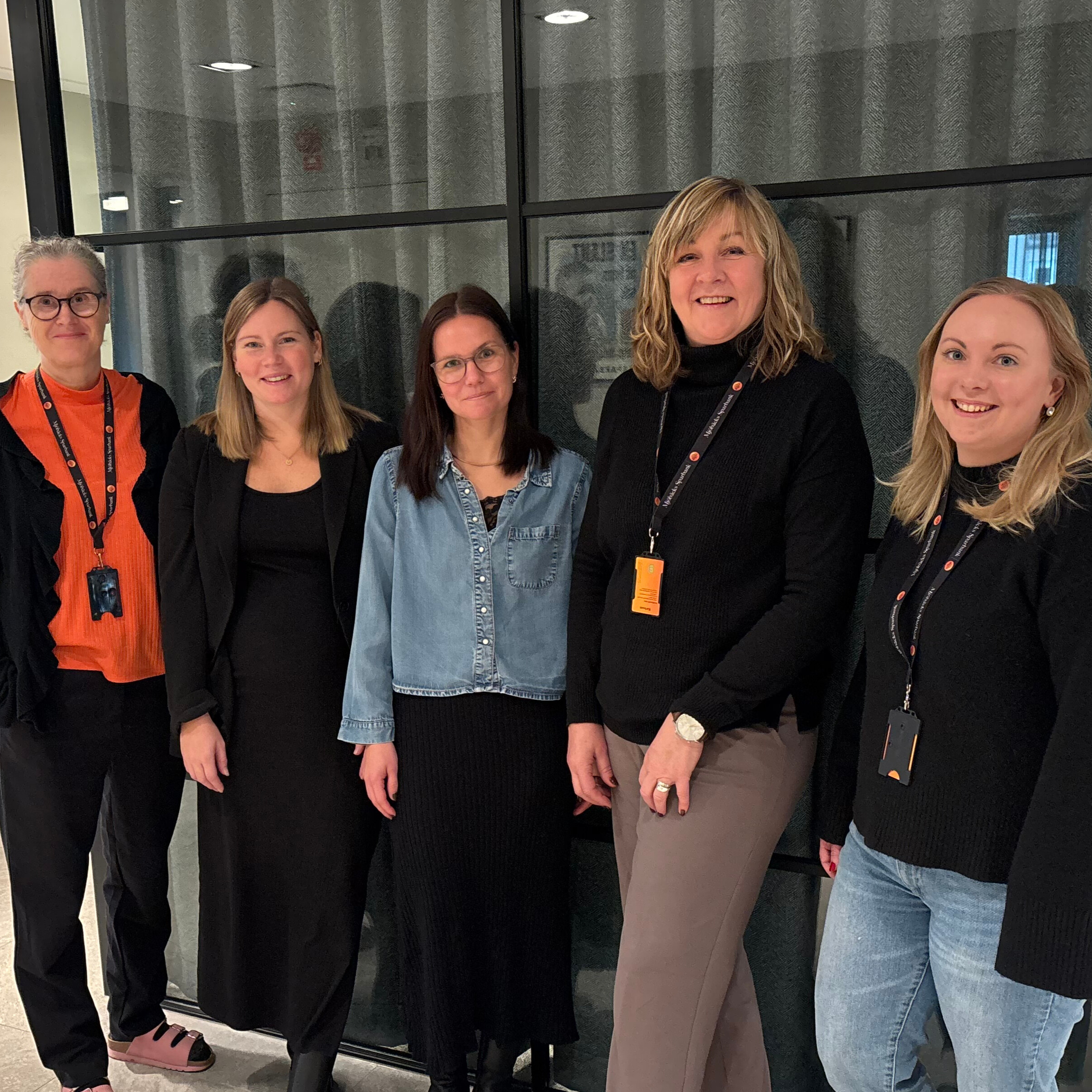 Lotta, Åsa, Jennifer, Lena och Nilla står framför en glasvägg och ler mot kameran