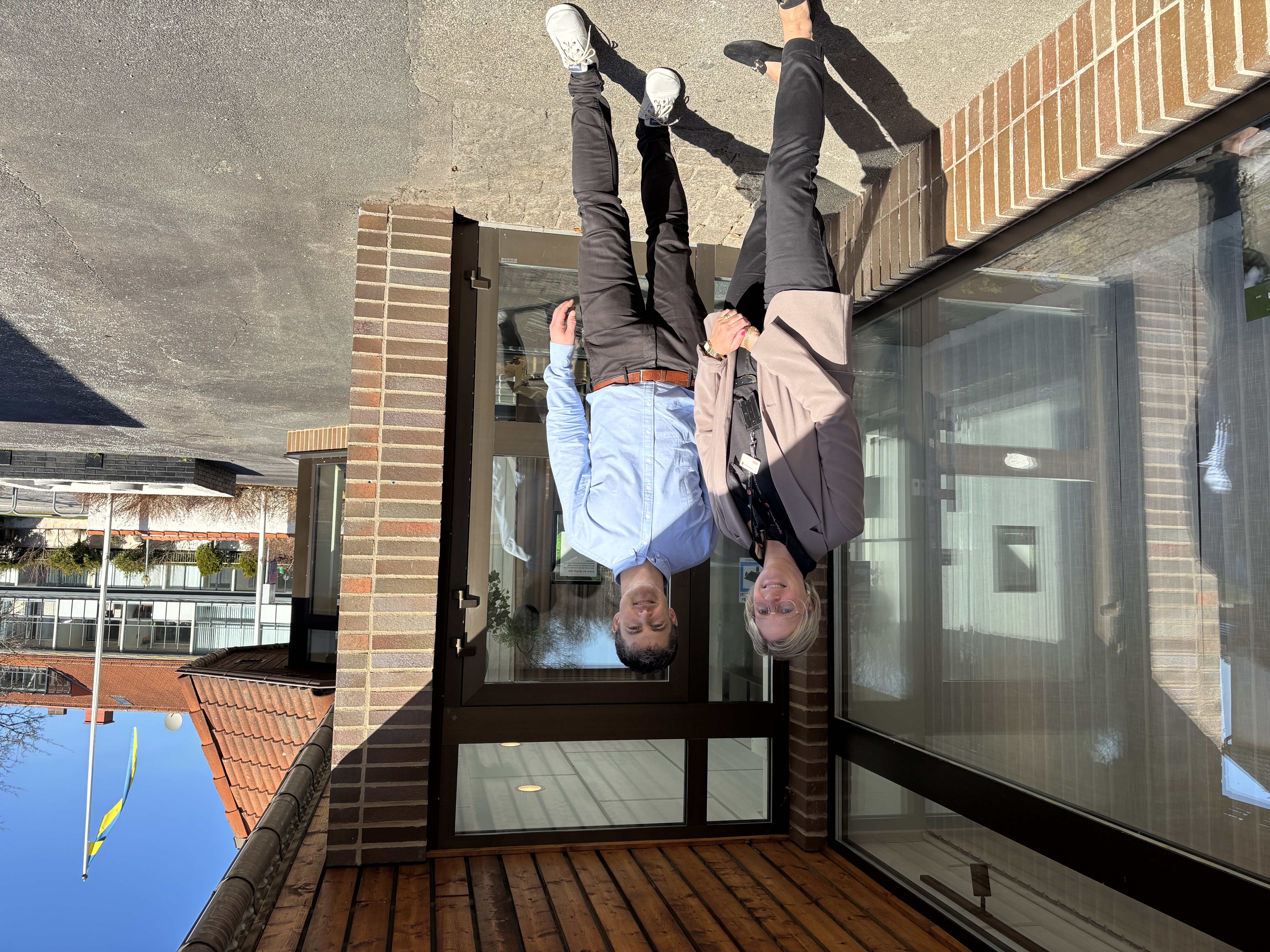 Anna och Tobias står utanför banken och ler mot kameran